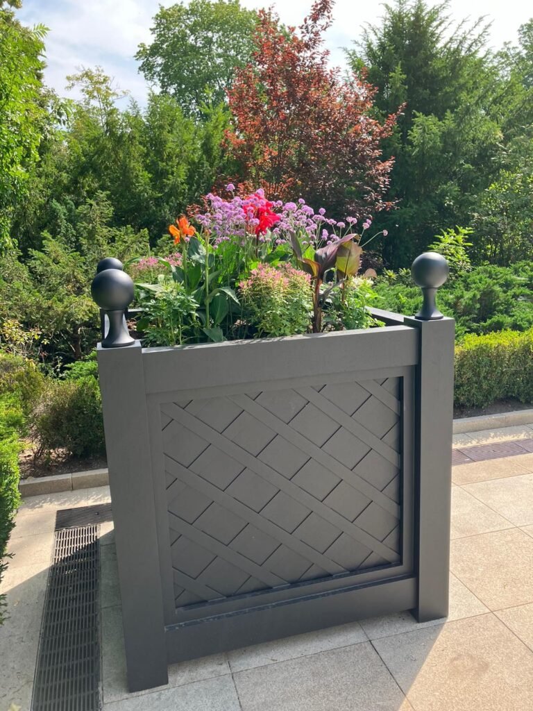 Exklusiver Outdoor-Pflanzkübel in Anthrazit mit geometrischem Muster, bepflanzt, im Garten